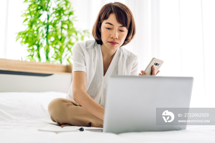 Young smiling happy beautiful asian woman relaxing using laptop computer on sofa at home.Young creative girl working and typing on keyboard.work from home concept