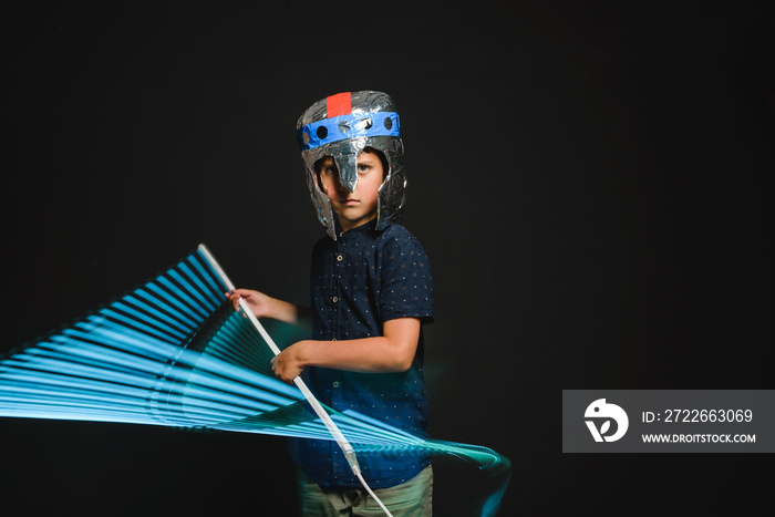 A kid with a lightsaber in his hands play in a superhero battle.