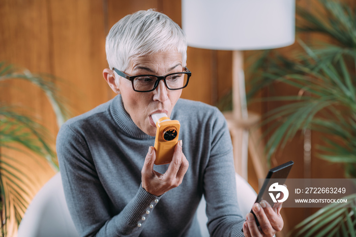 Senior Woman using Spirometer, Measuring Lung Capacity and Peak Expiratory Force