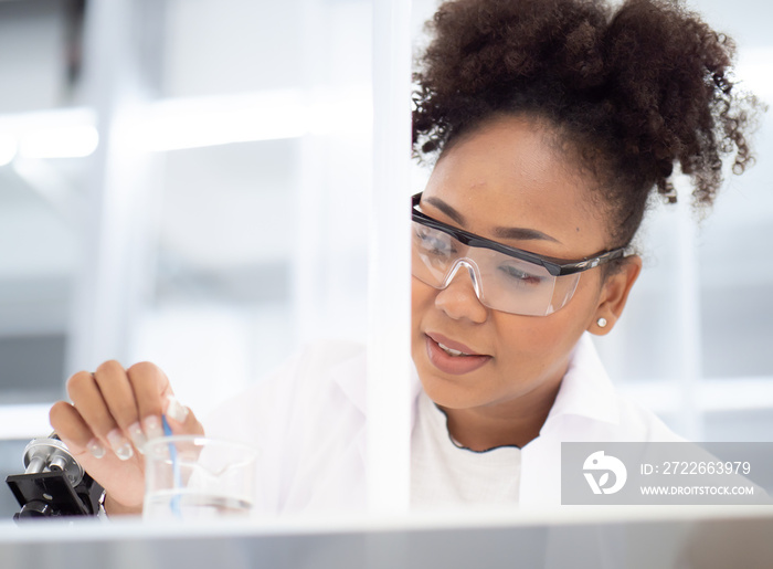 Scientist, chemist woman working in medical research laboratory experimenting chemistry liquid in beaker tube. African American student doctor studying, analyzing sample chemical in pharmaceutical lab