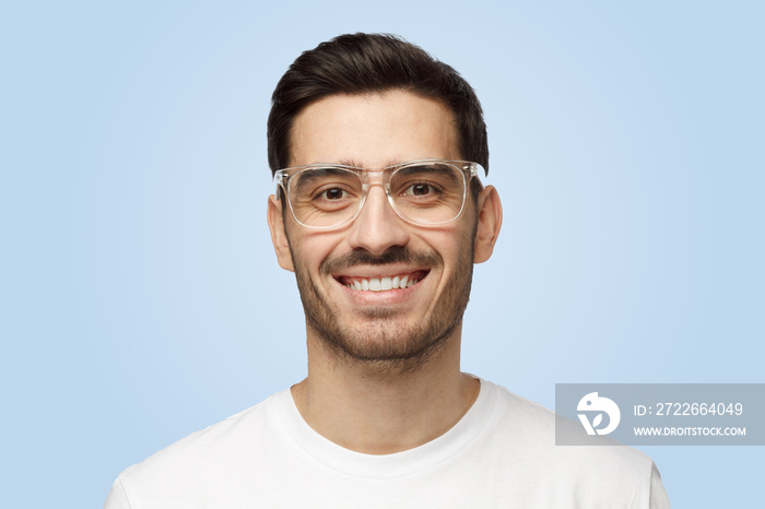 Attractive young Caucasian man in white T-shirt looks at camera and smiles positively