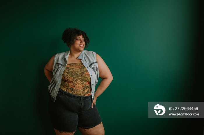 portrait of a plus size afro indigenous person standing in front of green background