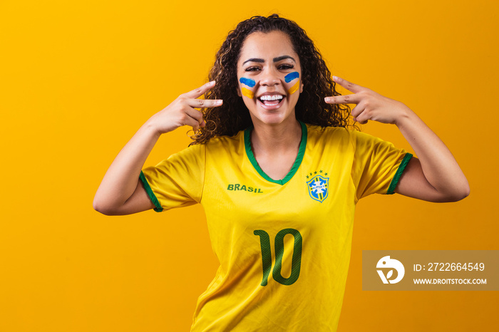 Brazilian supporter. Brazilian woman fan celebrating on soccer or football match on yellow background. Brazil colors.