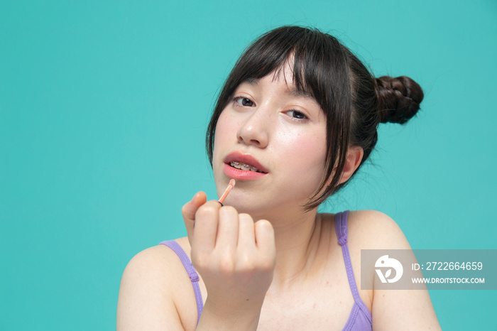 Studio portrait of girl applying lip gloss