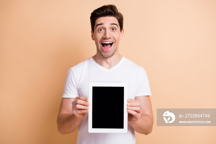 Profile portrait of impressed brunet man show tablet wear white t-shirt isolated on beige color background