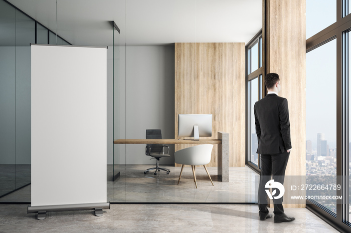 Blank white poster on concrete floor in modern loft style office and businessman