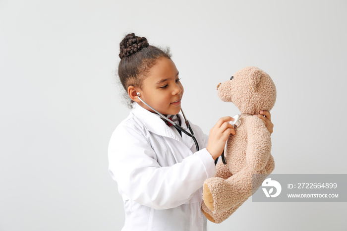 Portrait of little African-American doctor on white background