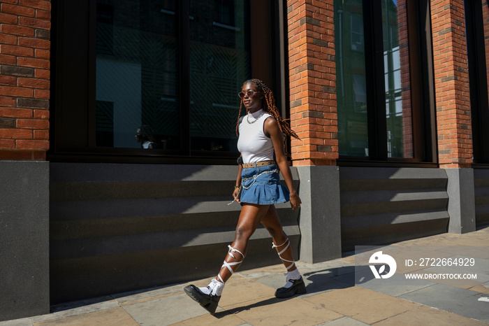 Woman wearing mini skirt and white top walking on sidewalk