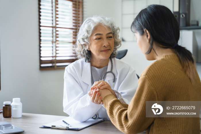 Friendly female doctor hands holding patient hand sitting at the desk for encouragement, empathy, cheering and support while medical examination.