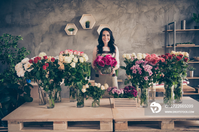 Portrait of her she nice attractive lovely charming cute cheerful cheery wavy-haired lady vendor holding in hands giving bunch greetings congrats birthday concrete wall indoors workplace