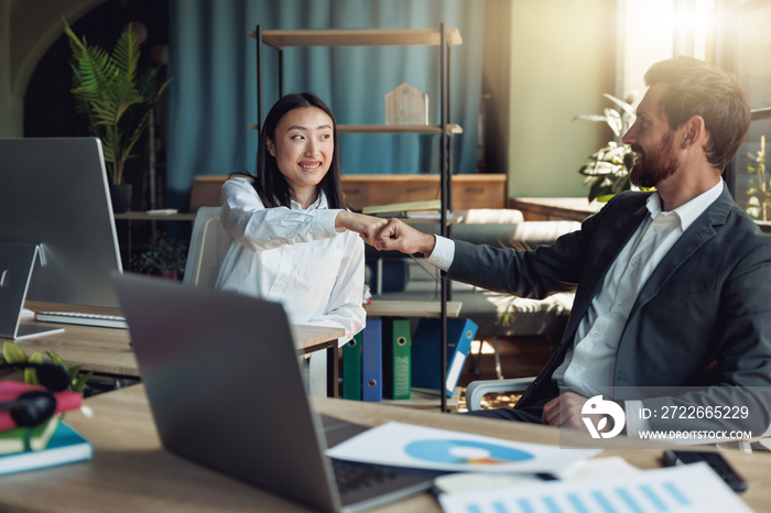 Two happy business colleagues clap hands after finishing work on project