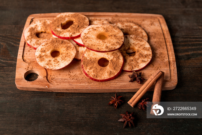 Close-up of juicy apple slices sprinkled with cinnamon placed on wooden board