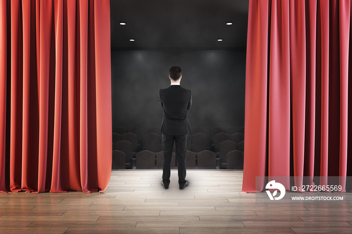 Back view of businessman looking at stage from behind red curtain. Entertainment, performance and presentation concept.