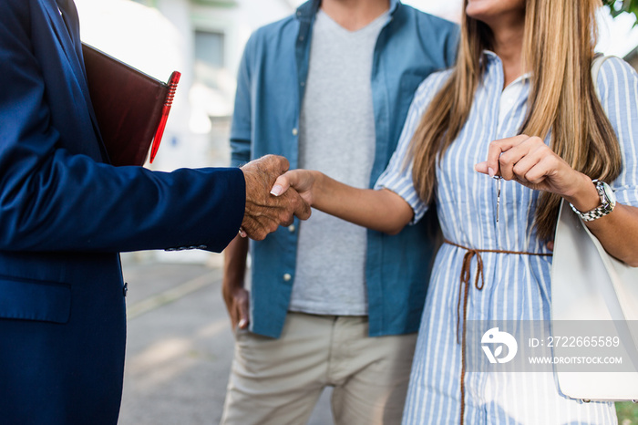 Young couple talking with real estate agent and buying a new house.