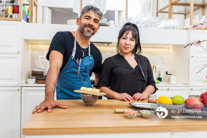 Portrait of two latin smiley chefs looking at camera in the kitchen. Cooks preparing the dinner for a private party.