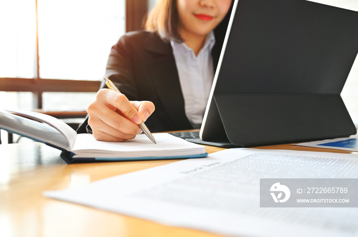 Audit business woman working with notebook and tablet on desk.