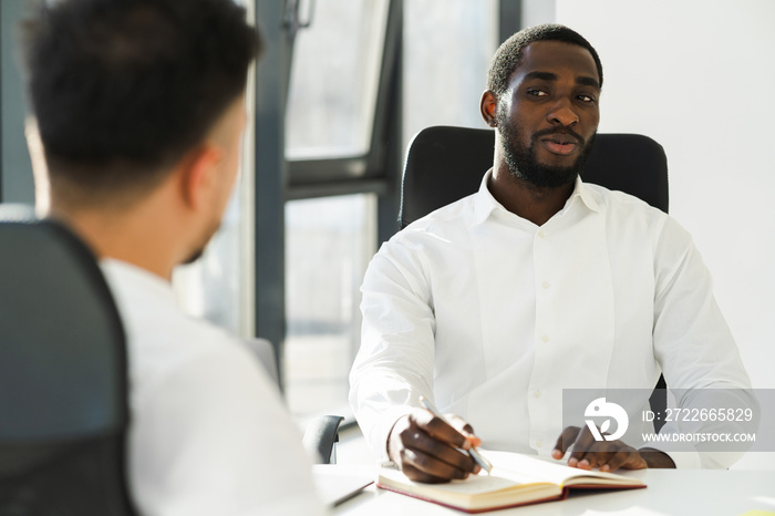 Black man in a white shirt is interviewing a new employee in a company