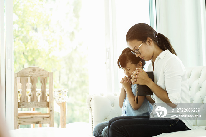 woman and little girl  praying on holy bible