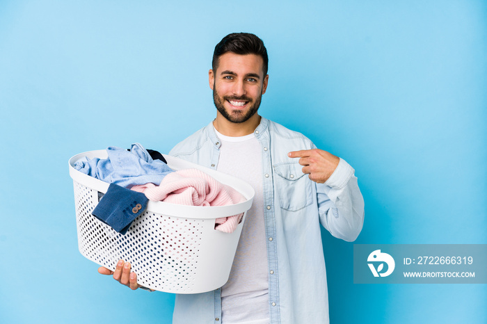 Young handsome man doing laundry isolated person pointing by hand to a shirt copy space, proud and confident