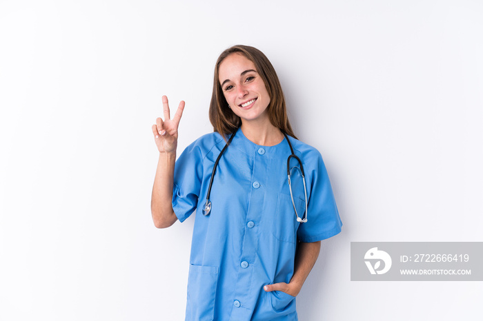 Young nurse woman isolated joyful and carefree showing a peace symbol with fingers.