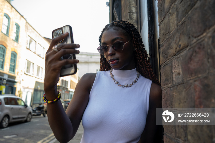 Woman wearing white top and sunglasses using smart phone