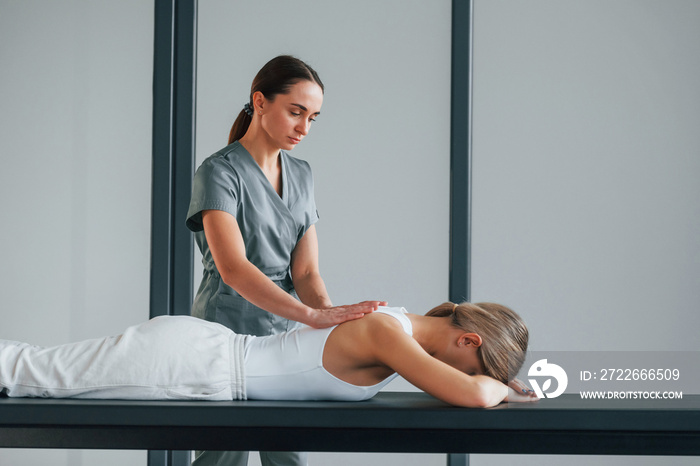 Massaging the back. Woman is in health center getting help by doctor