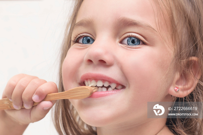 Small child brushes teeth with a bamboo toothbrush. Close-up face. Children’s health concept.