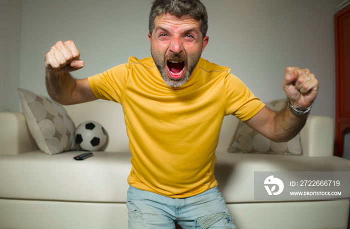 young excited and crazy happy football supporter man watching soccer game on television at living room sofa celebrating team scoring goal