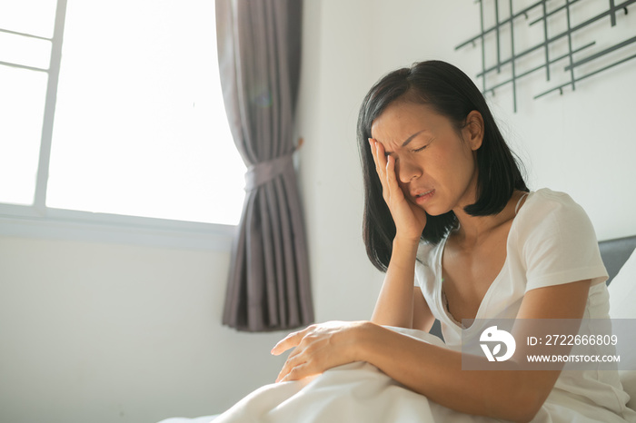 Young Asian woman feel toothache and discomfort on bed in white bedroom morning. concept of women health care. close-up view of young woman suffering from toothache while lying in bed.