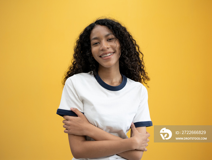 International Woman day power African American woman huge  embraces equity herself, feels good, fulfilled, has high self esteem, tilts head and smiling wears white shirt isolated on yellow background.