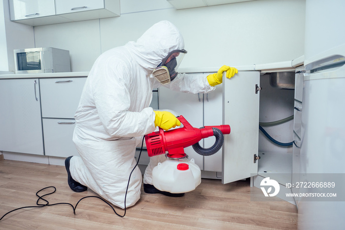 white worker spraying pesticide on induction hob