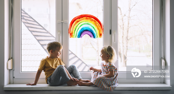 Little children on background of painting rainbow on window