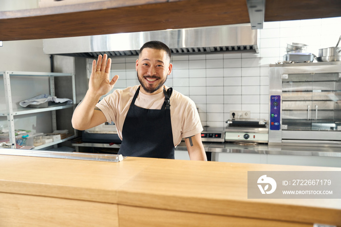 Frienldy restaurant staffmember waving from behind the counter