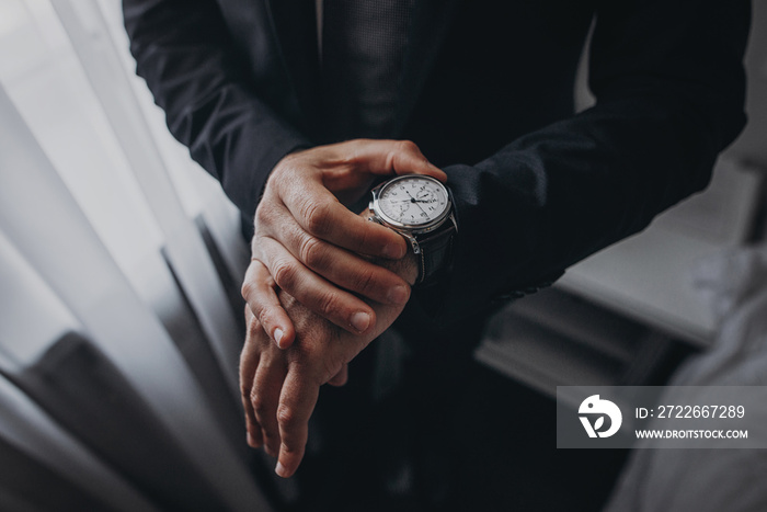 businessman checking time on his wrist watch, man putting clock on hand,groom getting ready in the morning before wedding ceremony