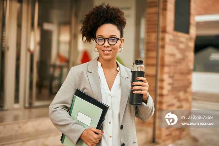 Young african american businesswoman holding bottle of water at the city.