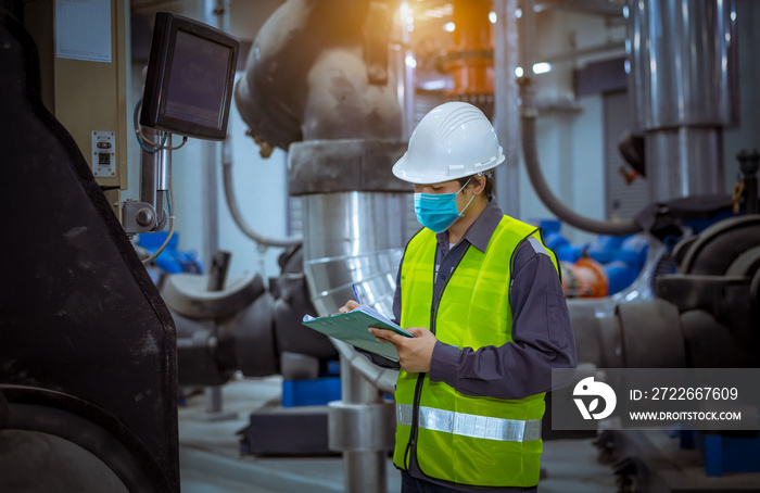 Engineer under checking the industry cooling tower air conditioner is water cooling tower air chiller HVAC of large industrial building to control air system ,wearing mask for protect pollution.