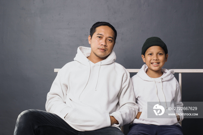 Asian Father and son sitting together wearing white hoodie for apparel mock up, isolated on gray background