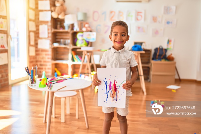 Beautiful african american toddler standing holding draw smiling at kindergarten