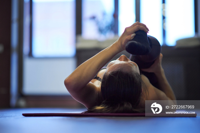 girl doing physical exercise and stretching legs on a mat, foot close up, healthy lifestyle concept. Side view of attractive young woman doing core exercise on fitness mat in the gym