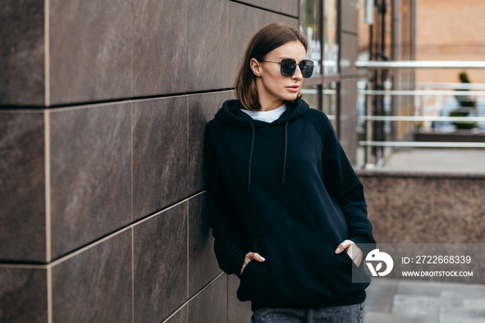 Young woman in glasses and black hoodie