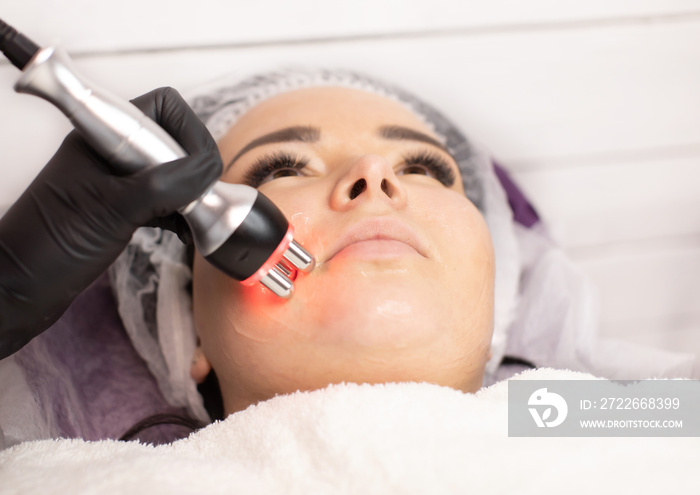 Hardware cosmetology. Closeup picture of happy young woman getting rf lifting procedure in a beauty parlour. Radio lifting.