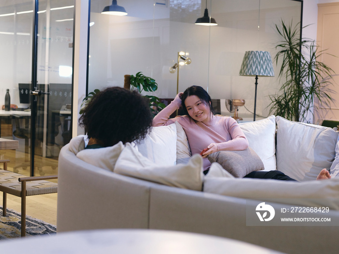 UK, London, Two female coworkers relaxing in modern office lobby