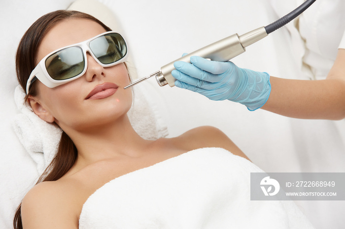 attractive woman receiving laser rejuvenation for her chin in beauty salon