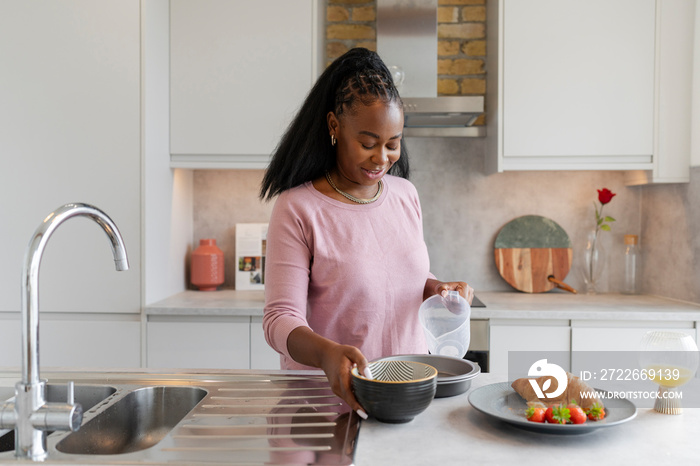 Smiling woman preparing breakfast in kitchen