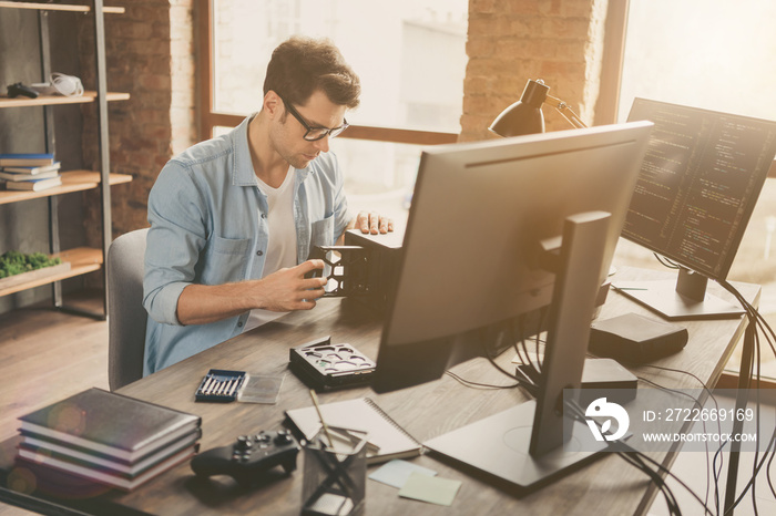 Portrait of his he nice attractive busy skilled experienced focused geek guy repairing part pc cpu hard disk drive handiwork at modern loft brick interior style work place station indoors