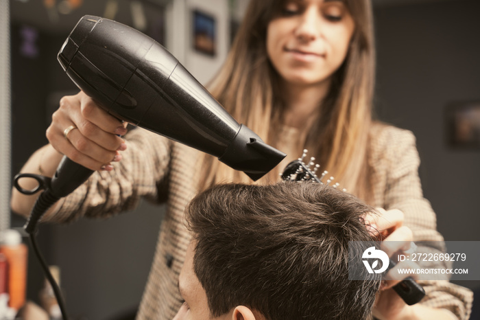 Hair salon master blow dry hair client at barber shop. Men’s fashion and style. Hair care, beauty industry, barber concept. Barber shop men hairstyle. Young man getting a modern haircut