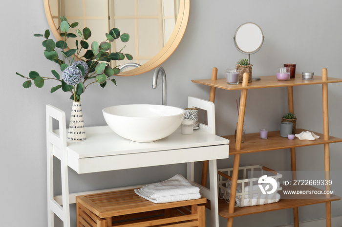 Sink, vase with flowers and eucalyptus on table in bathroom