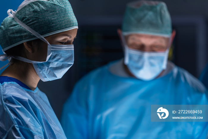 Multiracial team of professional medical surgeons performs the surgical operation in a modern hospital. Doctors are working to save the patient. Medicine, health, cardiology and transplantation.