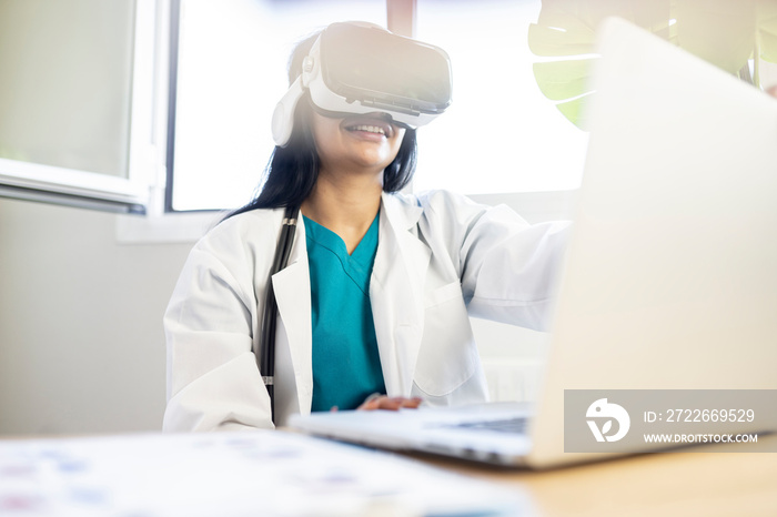 female doctor working with virtual reality headset in clinic while using laptop computer