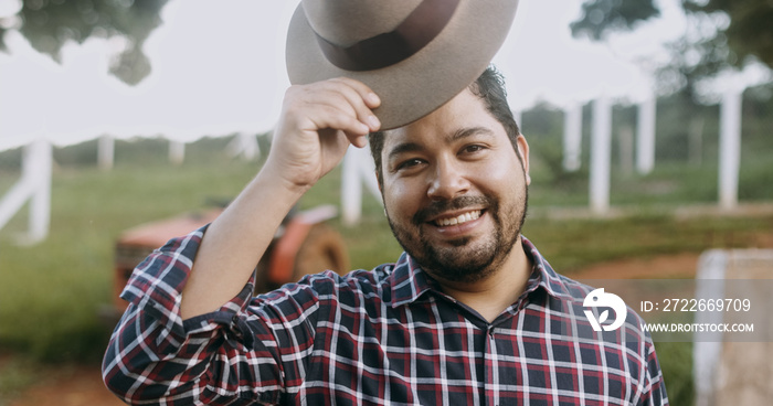 Portrait of young Latin farmer man in the casual shirt in the farm on the farm background.